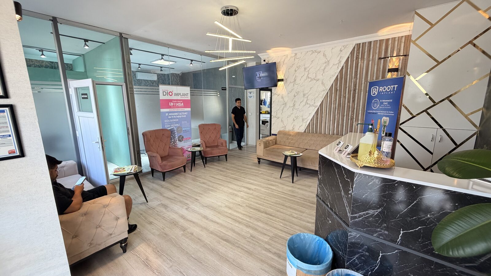 Kliniğin bekleme salonu; krem koltuklar, aydınlatma ve karşılama bankosu.