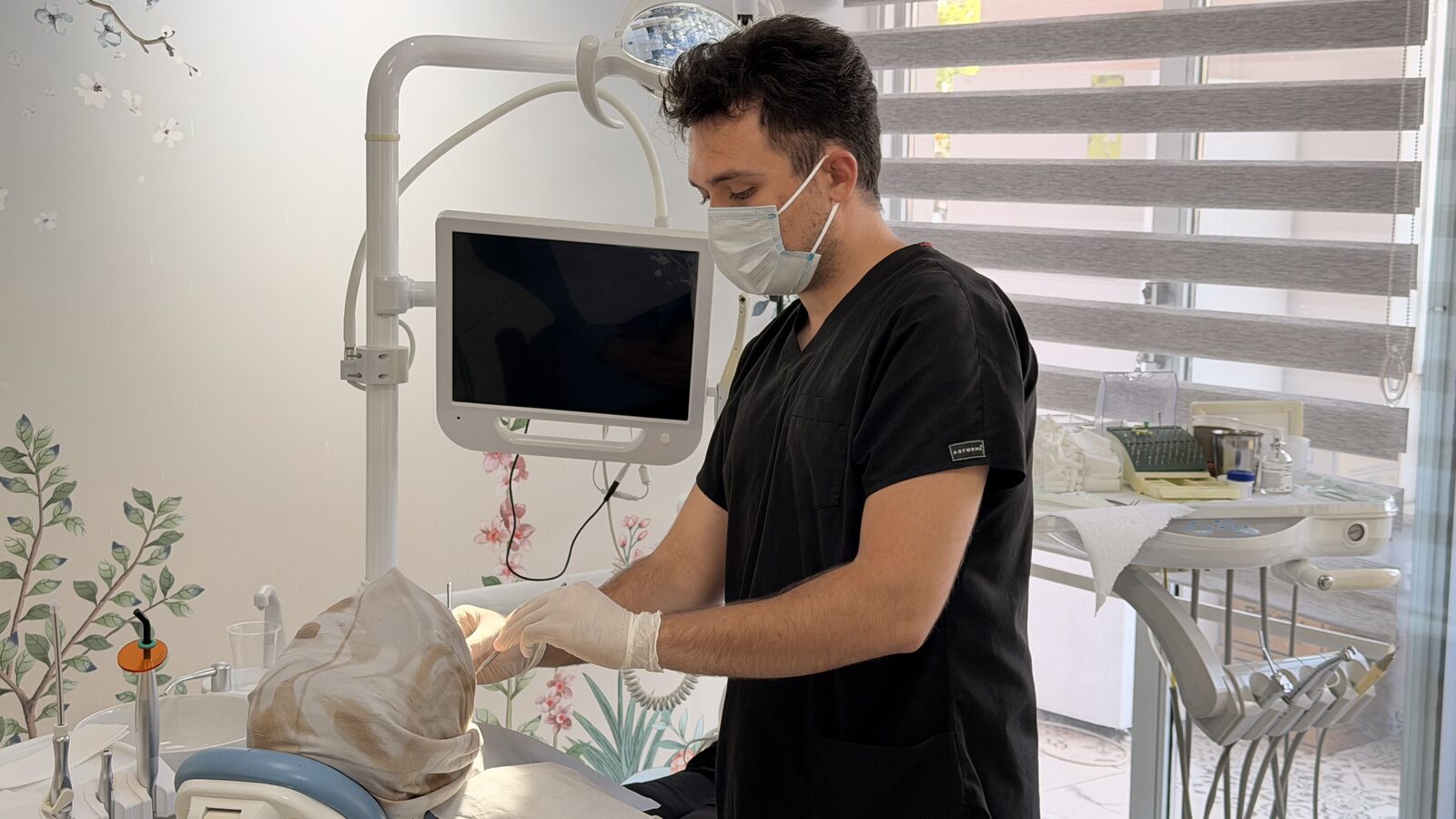 Diş hekimi maske ve eldivenle işlem öncesi hazırlık yaparken.